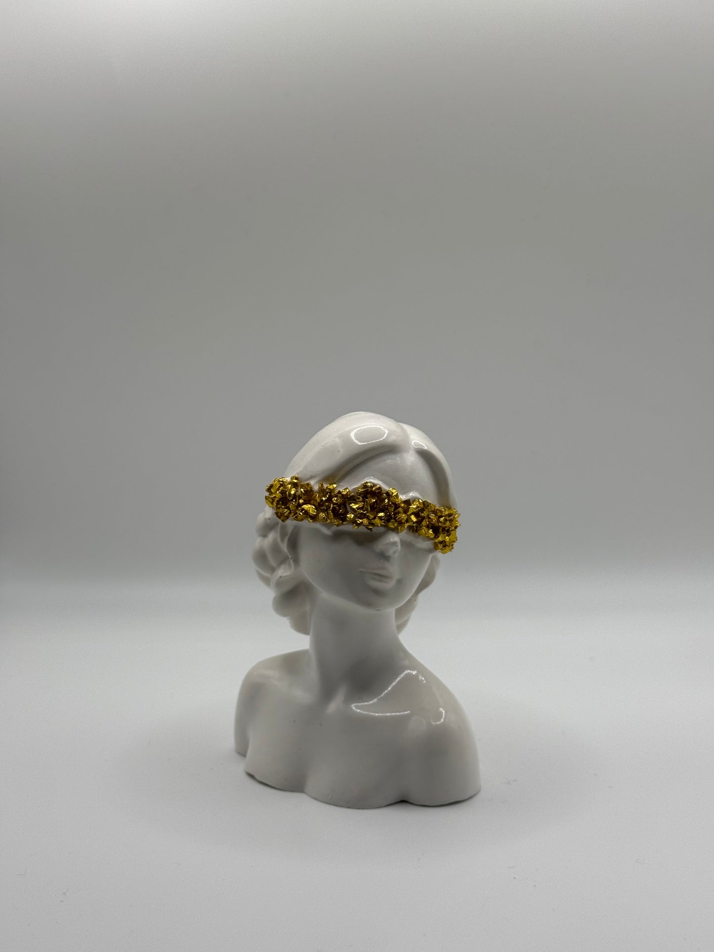 Frau mit verdeckten Augen und goldenen Steinen